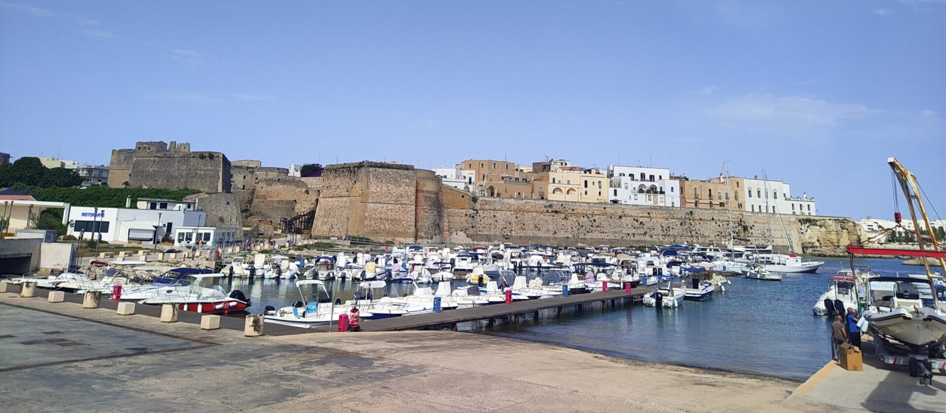 Otranto old town harbor with Aragonese walls and castle reflected in the crystal clear water