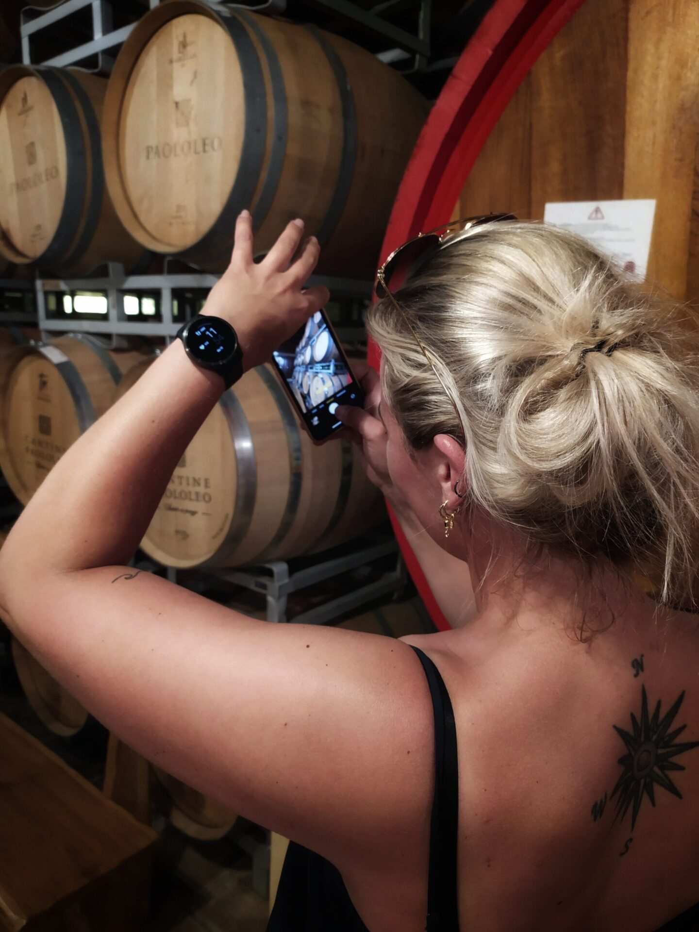 Visitor taking photos of oak barrels at Paolo Leo Winery in San Donaci, Salento