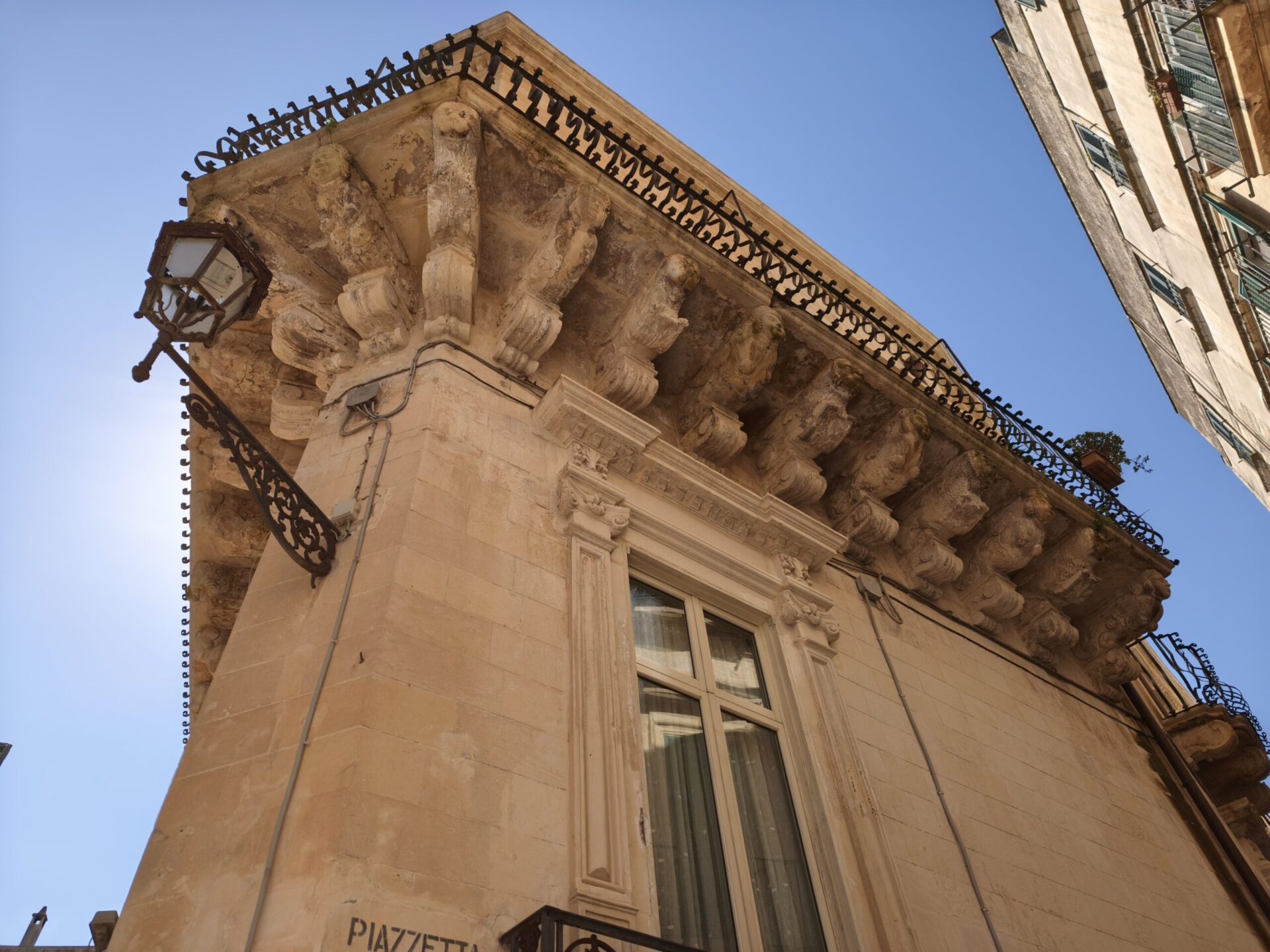 Intricate floral stone carving detail on a Baroque balcony in Lecce with garlands and putti