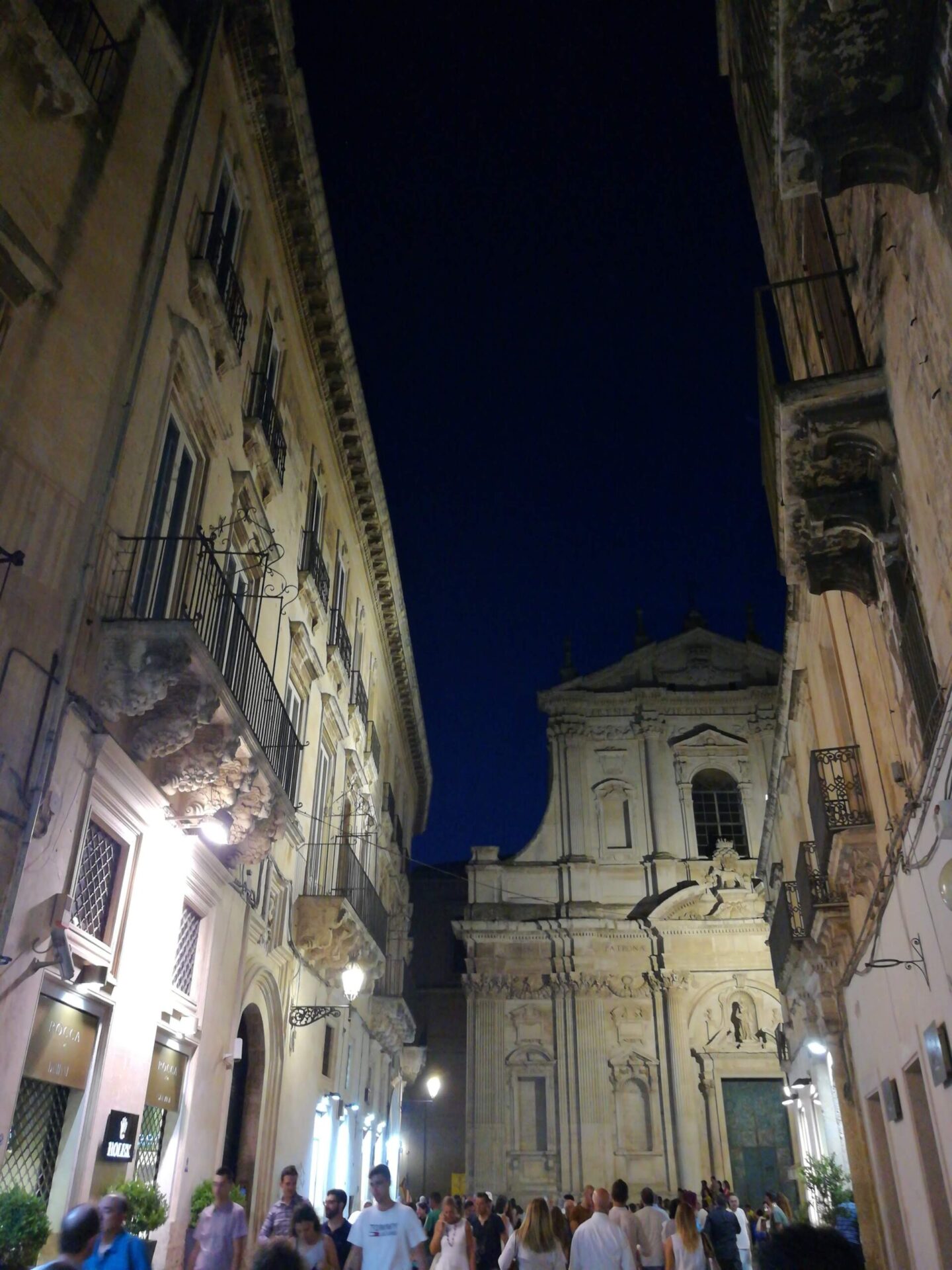 Evening view of Lecce's Santa Irene facade with warm street lamps illuminating baroque details