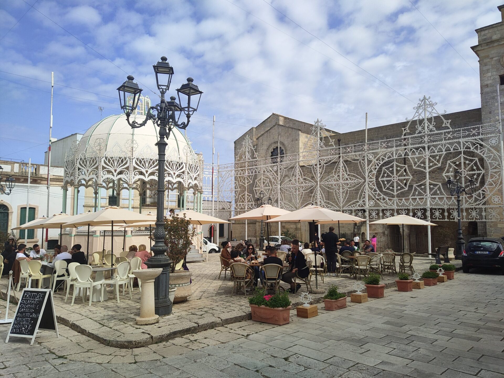 Piazza di paese nel Salento illuminata da luminarie tradizionali per una festa patronale